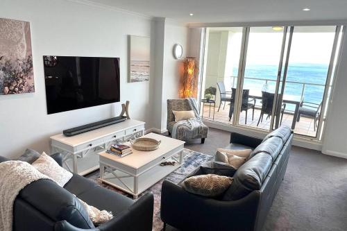 a living room with a couch and a flat screen tv at Amzing Ocean View Spacious Three Bedrooms Apartment Port Melbourne in Melbourne