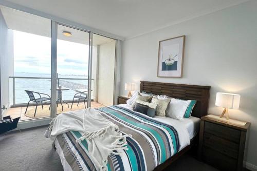 a bedroom with a bed with a view of the ocean at Amzing Ocean View Spacious Three Bedrooms Apartment Port Melbourne in Melbourne