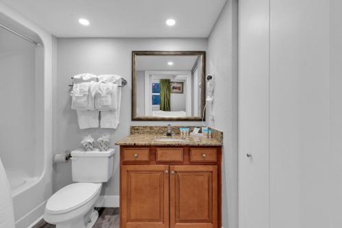 a bathroom with a toilet and a sink and a mirror at Oceanfront Atlantica 2BR Condo w Balcony in Myrtle Beach