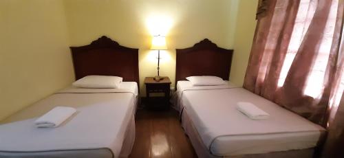 two twin beds in a room with a light on at Hotel Salcedo De Vigan in Vigan