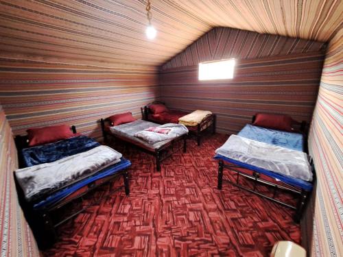 Habitación pequeña con 2 camas y alfombra. en Wadi rum galaxy camp en Wadi Rum