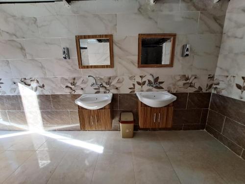 a bathroom with two sinks and two mirrors at Wadi rum galaxy camp in Wadi Rum