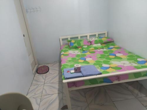 a small bedroom with a bed with a colorful comforter at Angeles City Guesthouse in Angeles
