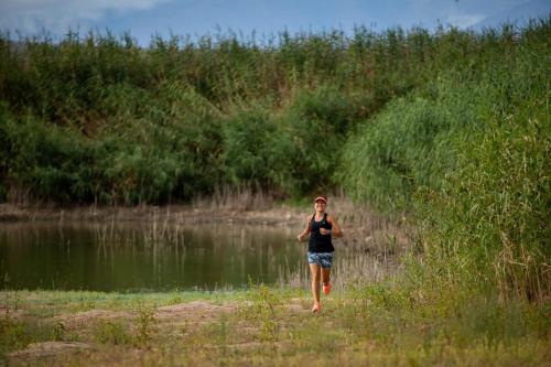 a woman walking down a path near a body of water at De Zeekoe Guest Farm in Oudtshoorn