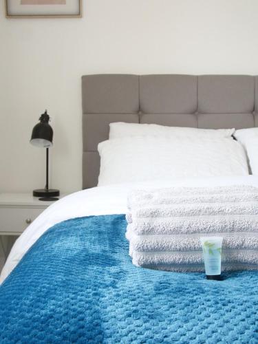 a bed with a pile of towels on it at Modern 2 Bed house - HS2, NEC & Birmingham Airport in Marston Green
