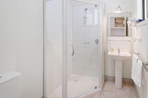 a white bathroom with a shower and a sink at Off Mountain Accommodation in Merrijig