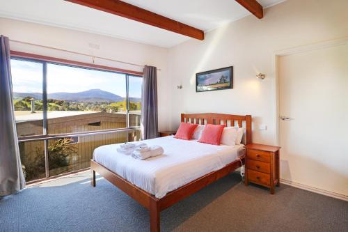 1 dormitorio con cama y ventana grande en Off Mountain Accommodation en Merrijig