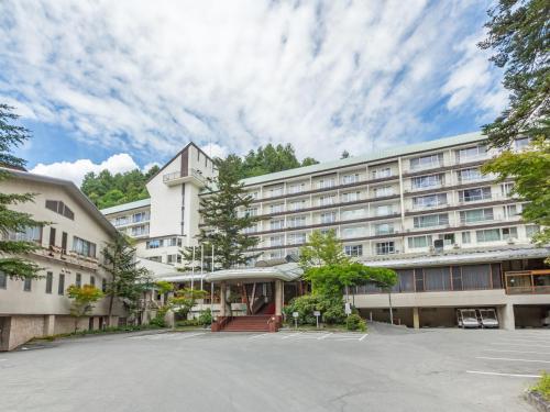 a large white building with a parking lot at Tateshina Grand Hotel Takinoyu in Chino