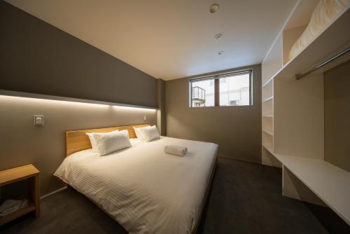a bedroom with a white bed with a window at Bluebird Apartments by The Hakuba Collection in Hakuba