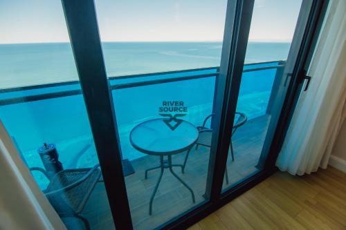 a glass door with a table and chairs in a room at Batumi River Source in Batumi