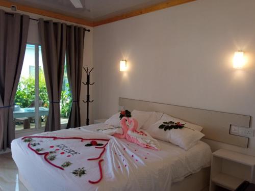 Thoddoo Garden inn في ثودو: غرفة نوم بها سرير عليه زهور
