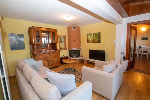 a living room with white couches and a tv at Villa Rina Deluxe and Cottage in Porto Ceresio