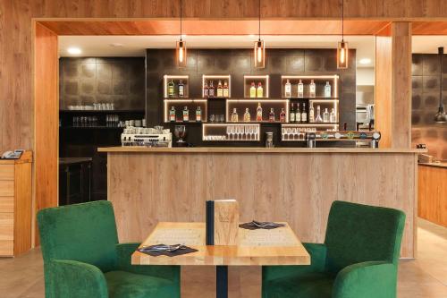 a bar with green chairs and a wooden table at Hotel Lípa in Dolní Lipová