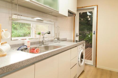 a kitchen with a sink and a washing machine at Bandi House in Seogwipo