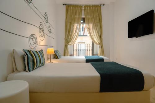 a bedroom with two beds and a television and a window at Smartr Madrid Chueca in Madrid