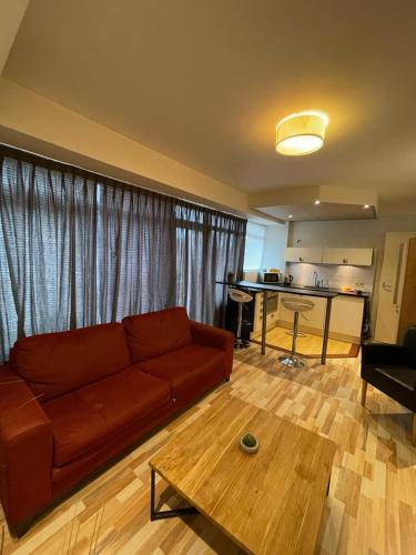 City Hotel Appartement Tilburg في تيلبورغ: غرفة معيشة مع أريكة حمراء وطاولة