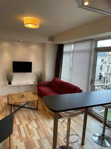 City Hotel Appartement Tilburg في تيلبورغ: غرفة معيشة مع أريكة حمراء وتلفزيون