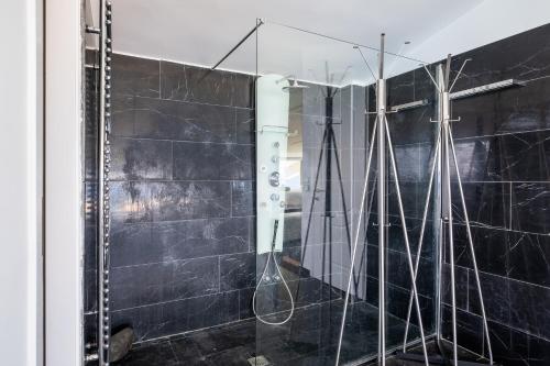 baño con ducha de azulejos negros en Icarus Luxury Beachfront Villa, en Gialiskari