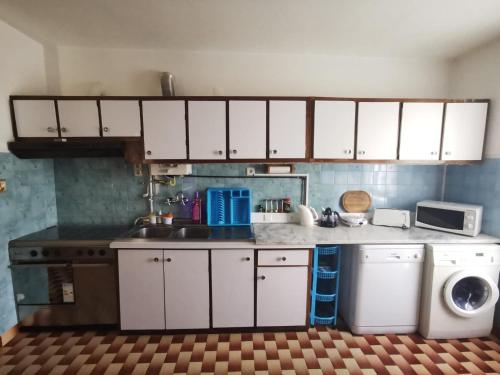a kitchen with white cabinets and a washing machine at O Mercadinho in Poiares