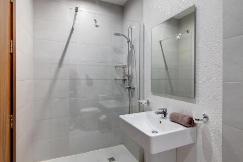 a white bathroom with a sink and a shower at Idyllic Apartment just off the Promenade in Sliema