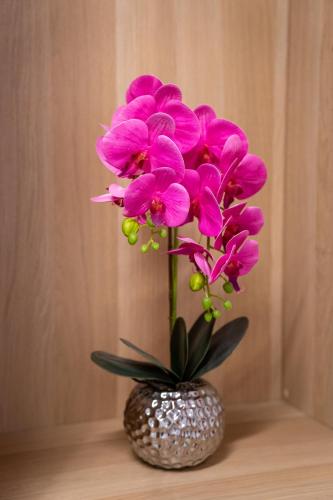 a vase filled with pink flowers on a table at Apartment of Közraktár in Budapest