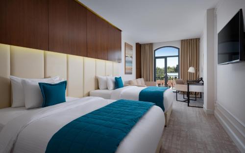 タシュケントにあるMercure Tashkentのベッド2台とダイニングエリアが備わるホテルルームです。