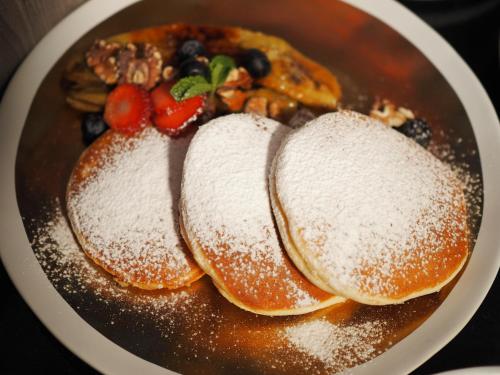 two pancakes with powdered sugar and fruit on a plate at The Coach Hotel Sukhumvit - Asok BTS Bangkok in Bangkok