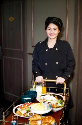 a woman standing in front of a table of food at The Coach Hotel Sukhumvit - Asok BTS Bangkok in Bangkok