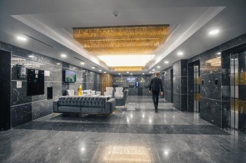 a man walking through a lobby with a couch and chairs at Royal Tulip Hotel & Casino, Tbilisi in Tbilisi City