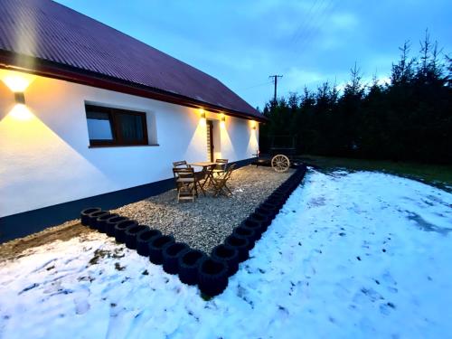 a white house with a table and chairs in the snow at Domek Góralski na Ubocy z jacuzzi in Białka Tatrzanska
