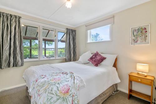 ein Schlafzimmer mit einem Bett und zwei Fenstern in der Unterkunft Carrington Countryside - New Plymouth Holiday Home in New Plymouth