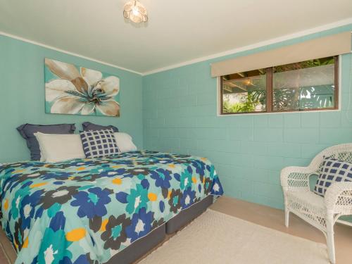 Dormitorio azul con cama y ventana en Purely Pauanui - Pauanui Holiday Home en Pauanui