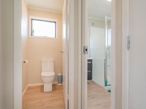 a bathroom with a toilet and a window at Purely Pauanui - Pauanui Holiday Home in Pauanui