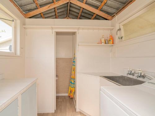 a kitchen with white cabinets and a ceiling with a window at Purely Pauanui - Pauanui Holiday Home in Pauanui