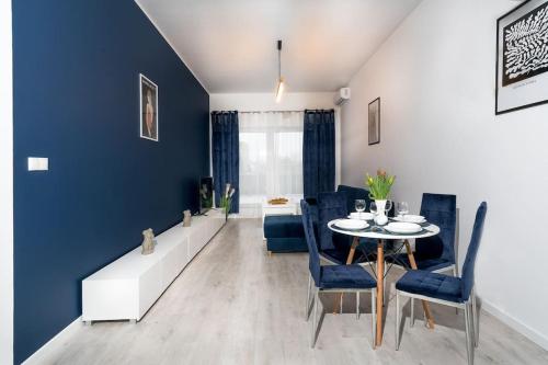 ein Esszimmer mit blauen Wänden sowie einem Tisch und Stühlen in der Unterkunft Regal Park in Elblag