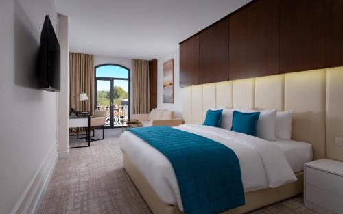 a hotel room with a large bed and a television at Mercure Tashkent in Tashkent