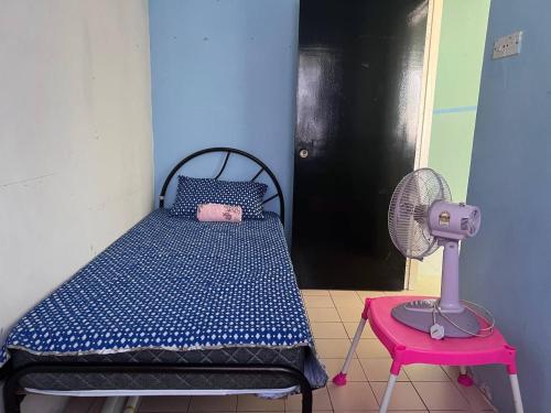 um quarto com uma cama, uma ventoinha e uma mesa em Maju Homestay em Gerik