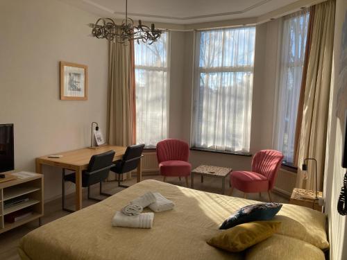 een slaapkamer met een bed en een tafel en stoelen bij Plato by Hofstad Studio’s in Scheveningen