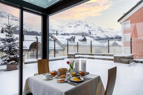 a dining table with a view of snow covered mountains at Albana Hotel Silvaplana in Silvaplana