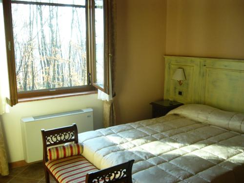 a bedroom with a bed and a window and a chair at Albergo La Foresteria in Bettolle