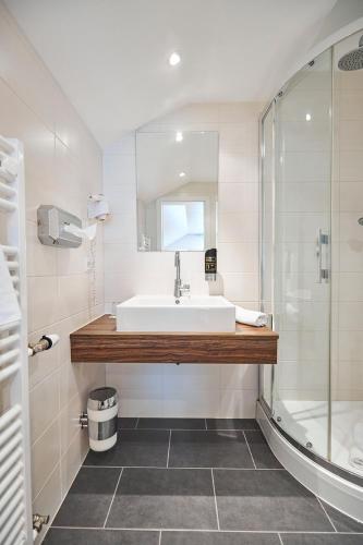 a white bathroom with a sink and a shower at ERCK- Flair Hotel & Restaurant in Bad Schonborn