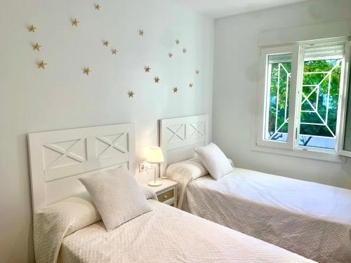 um quarto branco com 2 camas e uma janela em Islantilla Luxury em Isla Cristina