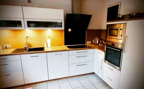 a kitchen with white cabinets and stainless steel appliances at Die Ibbenbürener Ferienstube in Ibbenbüren