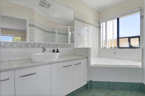 a white bathroom with a sink and a mirror at Daydream by the Sea! in Mandurah