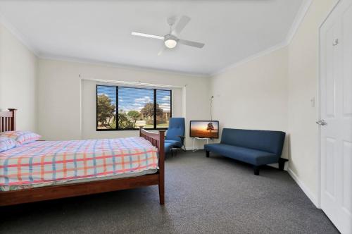 a bedroom with a bed and a chair and a window at Daydream by the Sea! in Mandurah