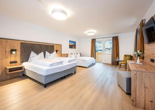 Habitación de hotel con 2 camas y escritorio en Hotel Brunner - Reiteralm, en Schladming