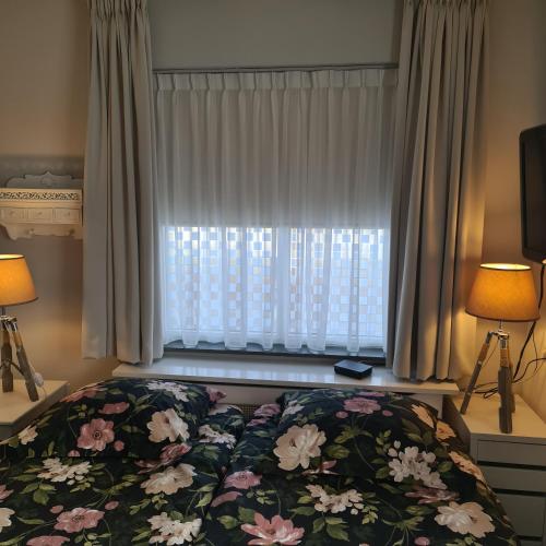 a bedroom with a bed and a window with flowers at LandLust Guesthouse B&B Amsterdam Area Purmerend in Purmerend