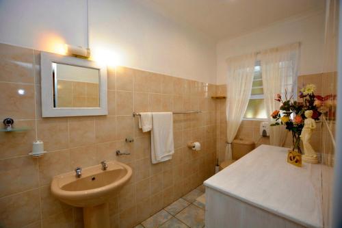 a bathroom with a sink and a toilet and a mirror at Amarachi Guesthouse in Swakopmund