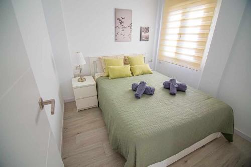 ein Schlafzimmer mit einem Bett mit zwei violetten Bogen darauf in der Unterkunft New Apartamento centro de Torremolinos con Parking in Torremolinos