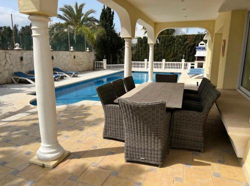 eine Terrasse mit einem Tisch und Stühlen neben einem Pool in der Unterkunft Beautiful villa 2 steps from the BEACH in Marbella